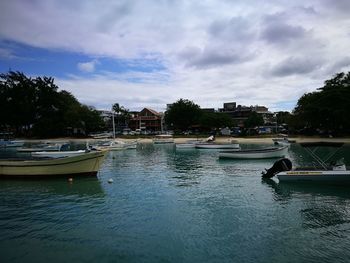 Boats moored in river against sky in city