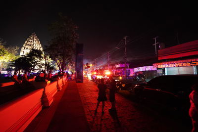 People on illuminated street in city at night