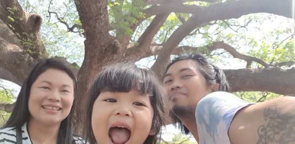 Portrait of smiling girl and plants against trees