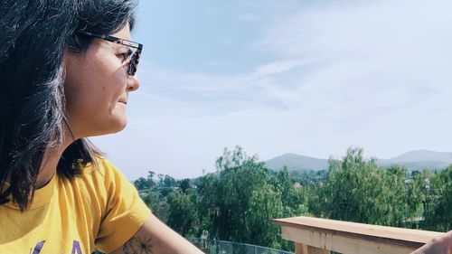 Portrait of young woman looking at camera against sky