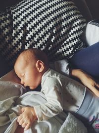 Midsection of mother lying with newborn son on bed