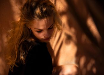 Side view of teenage girl sitting against wall