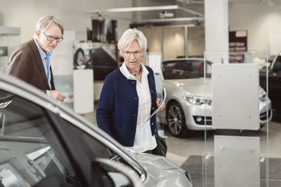 Senior couple looking at car in showroom