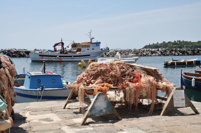 Fishing boats moored at harbor against sky