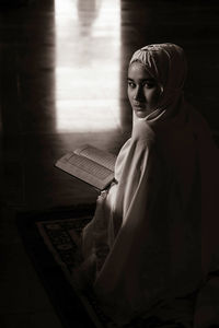 Portrait of young woman in hijab reading koran