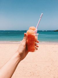 Close-up of hand holding ice cream on beach