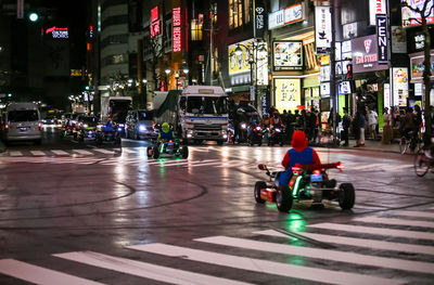 People riding motorcycle on road in city at night