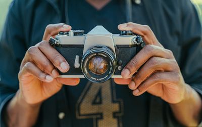 Midsection of man holding camera