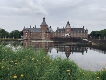 View of buildings by river against cloudy sky