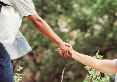 Midsection of man holding hand of woman