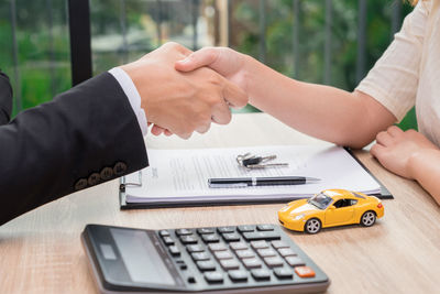 Midsection of people holding hands on table