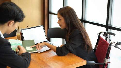 Young woman using mobile phone while sitting on table