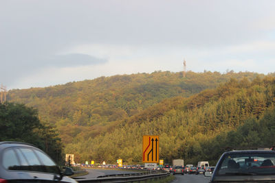 Cars on road against cloudy sky