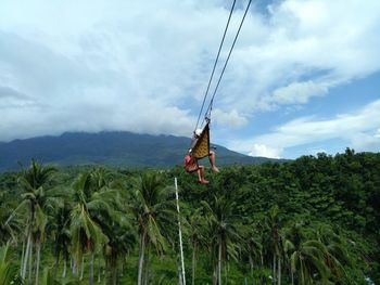 People on zip line against mountain