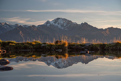 Scenic view of lake by mountains against sky during sunset