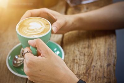 Midsection of woman holding coffee cup on table