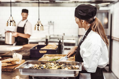 Female chef chopping vegetables in commercial kitchen