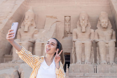 Portrait of young woman standing against building