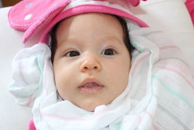 Close-up portrait of baby girl lying on bed