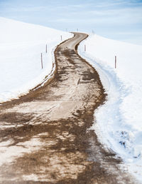 Snow covered land by sea against sky