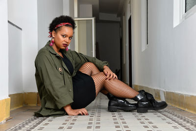 A pretty young african american confident woman in the stairwell of an old apartment building.