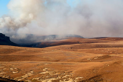 Smoke emitting from volcanic landscape against sky