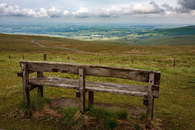 Bench on field against sky