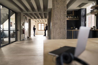 Business people talking while leaning on wall at office