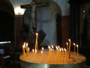 Illuminated candles in temple against building