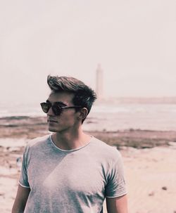 Portrait of young man wearing sunglasses standing on beach