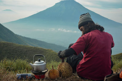 Rear view of man standing by mountains against sky