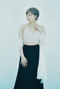 Portrait of young woman standing against white background