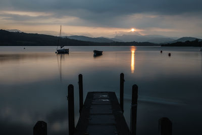 Pier over lake against cloudy sky