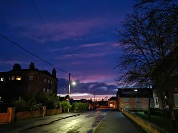 Street amidst buildings against sky at dusk