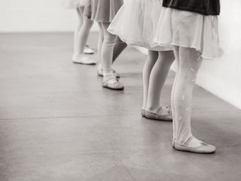Low section of ballet dancers standing on hardwood floor