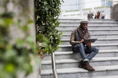 Man sitting on staircase using tablet