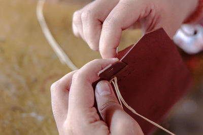 Close-up of woman hands making leather wallet in workshop