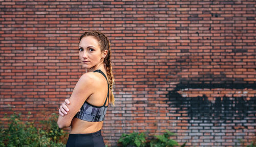 Portrait of woman standing against brick wall