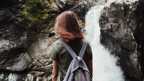 Rear view of woman with backpack looking at waterfall