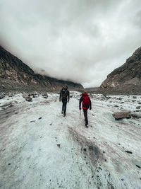 Two climbers hiking on glacier under cloudy sky