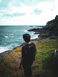 Rear view of man looking at sea against sky