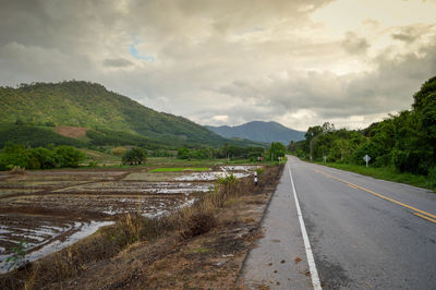 Road leading towards mountains against sky