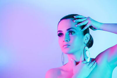 Young woman looking away against colored background