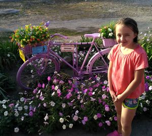 Full length of girl standing by flowering plants