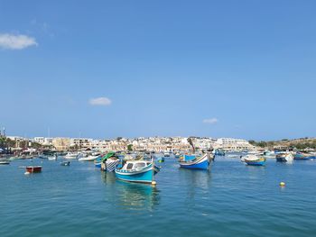 Sailboats moored in sea against sky