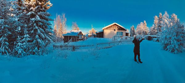 Man standing by building against sky during winter