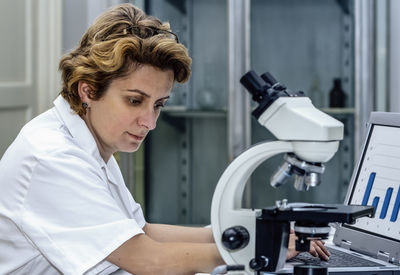 Close-up of scientist using laptop while sitting at laboratory