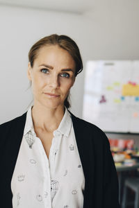 Portrait of confident mid adult businesswoman standing at creative office