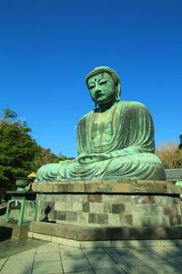 Low angle view of statue against clear blue sky