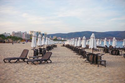 Empty chairs on beach against sky